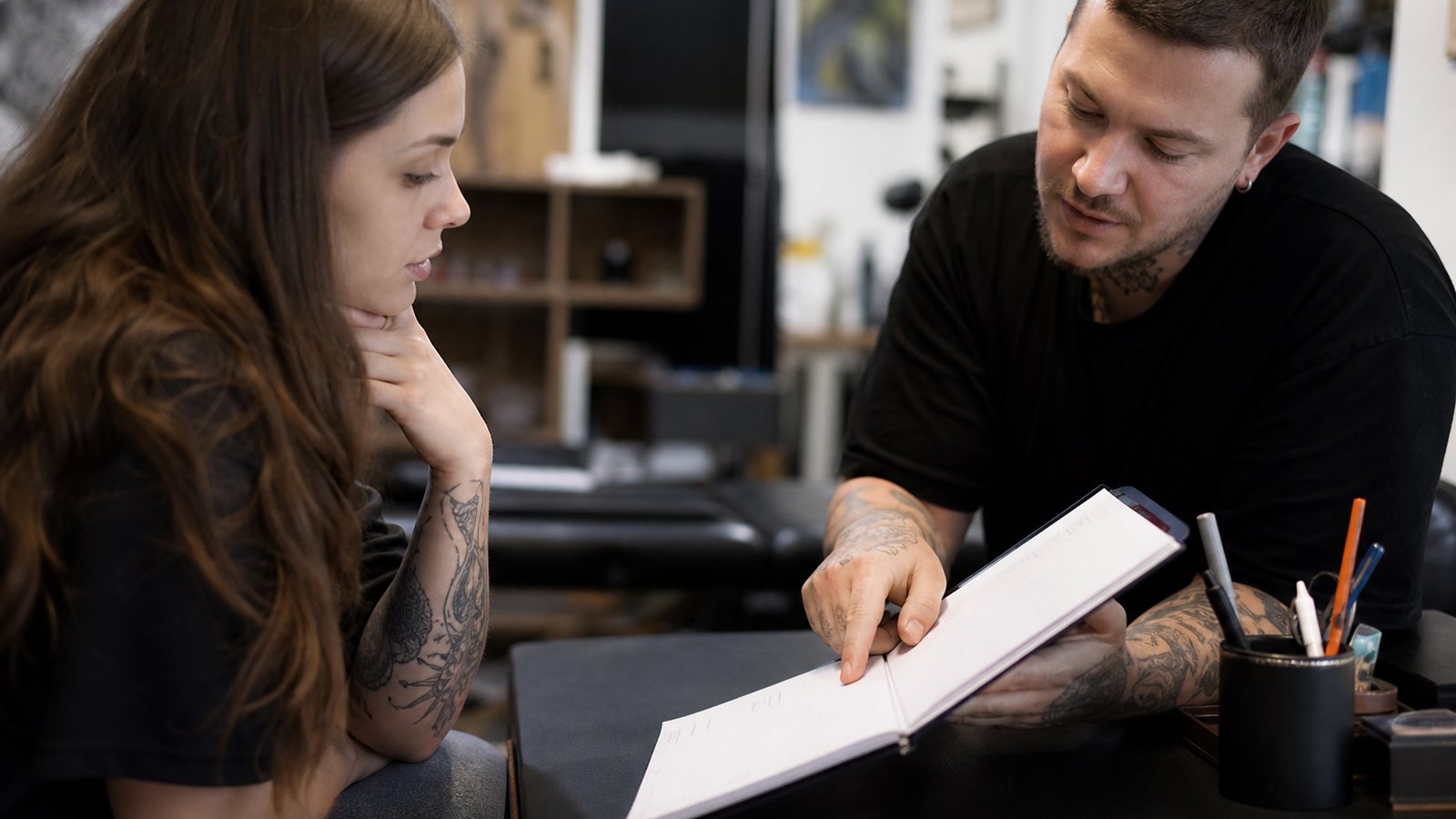 Tatoueur expliquant le déroulé d'une séance à un client avant signature